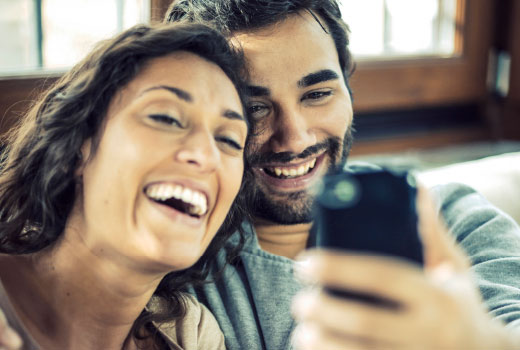 Une femme et un homme font un selfie avec un smartphone.